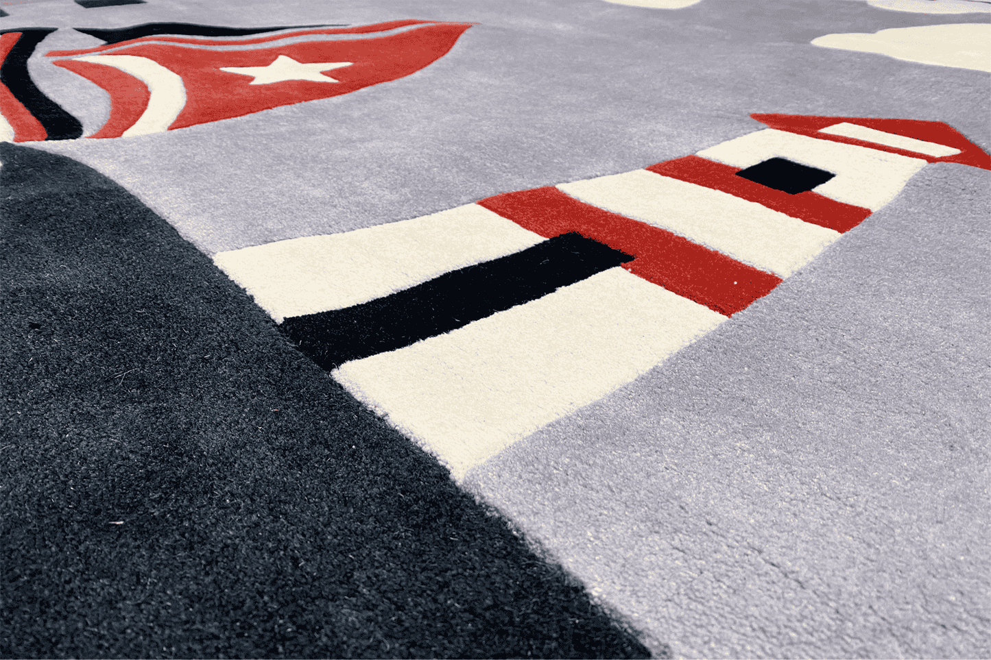 Detail of children's sailing boat rug: red and black elements of the lighthouse and sailing boat