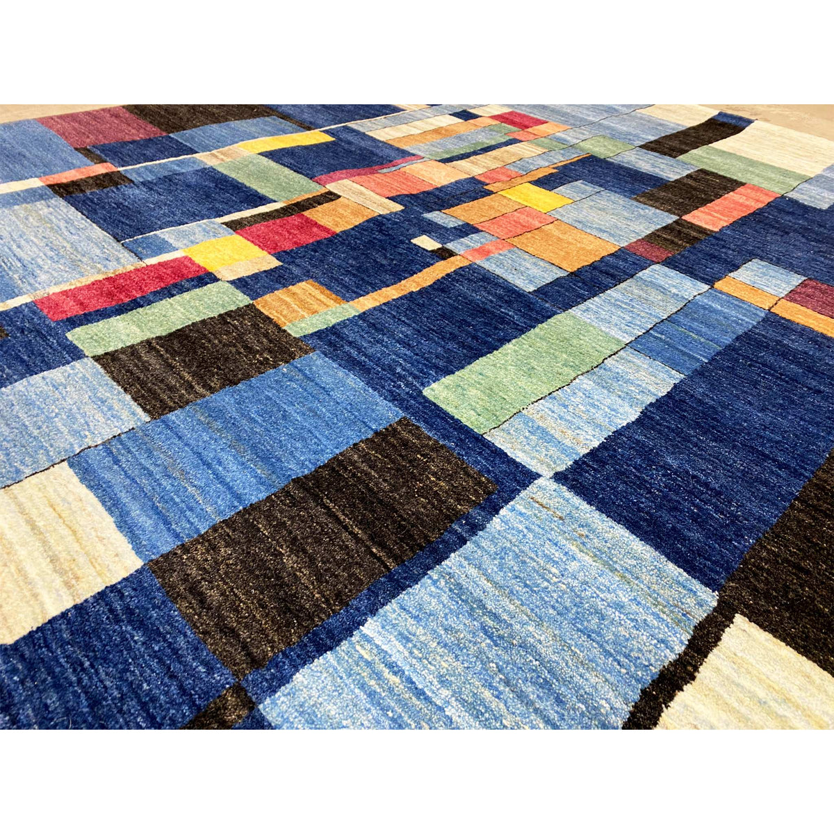 Close-up: Hand-knotted Gabbeh rug with blue patchwork and colorful accent squares
