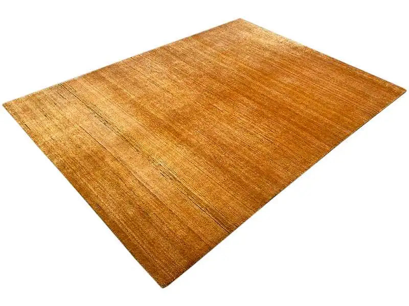 Gabbeh rug in gold, angled, solid-colored surface with subtle grain