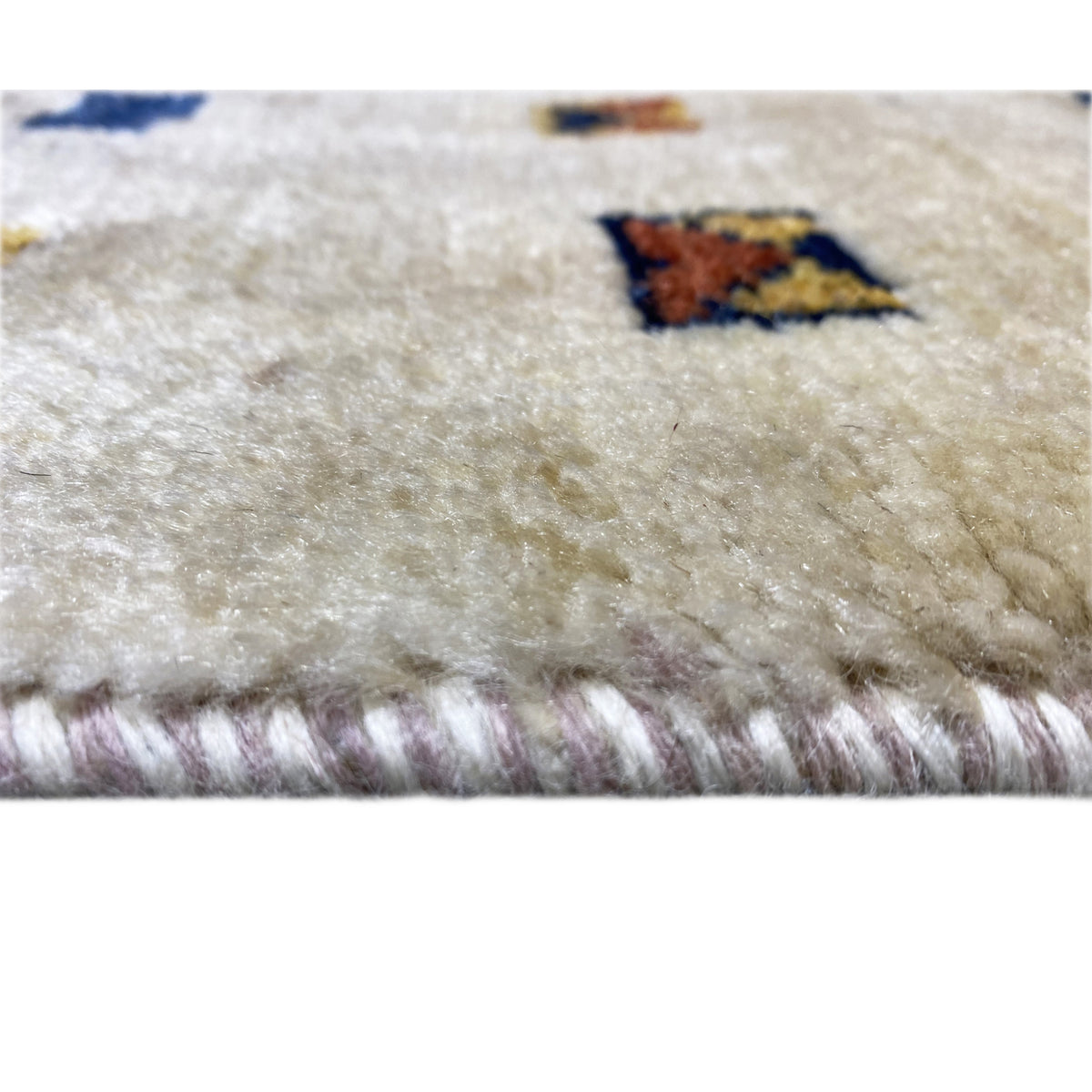 Close-up of a Gabbeh rug: beige pile with a frayed edge