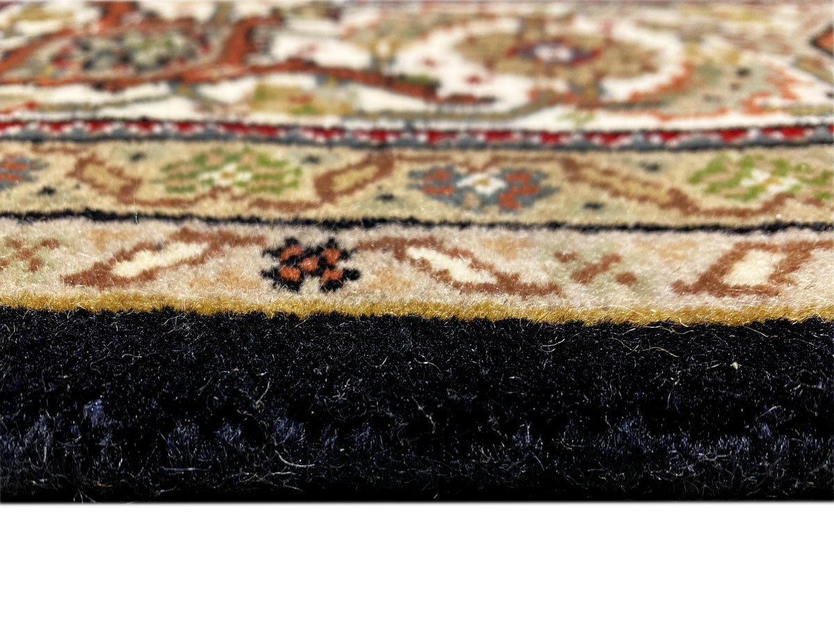 Teppichsaum im Detail: schwarzer Flor am Rand, darunter gemustertes Ornamentband