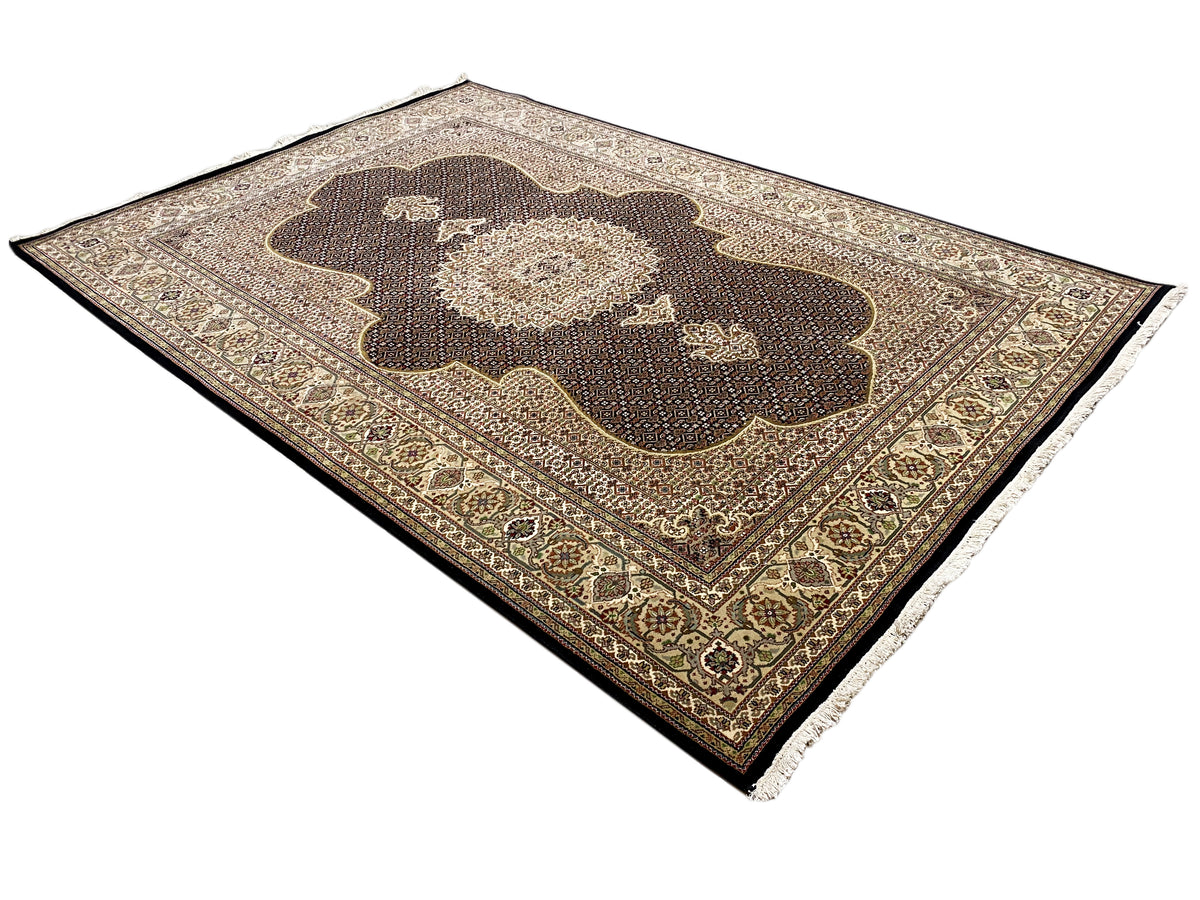 Teppich in Dunkelbraun mit beigem Ornamentfeld und goldener Bordüre, mit Fransen