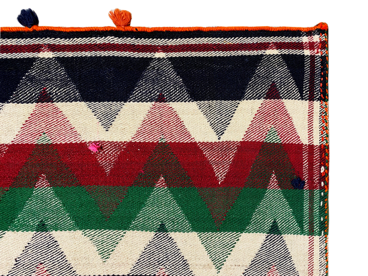 Close-up of a Jajim rug: bold triangular and striped patterns with orange tassels