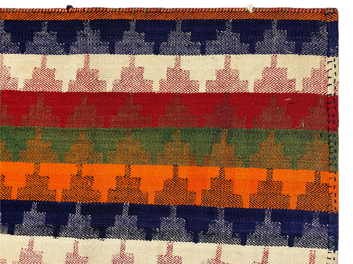 Close-up of a carpet: colored striped bands with a pattern of checkered/grid elements