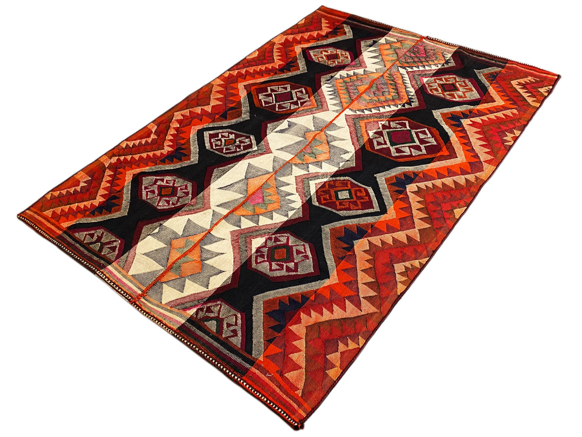 Jajim rug angled view: diamonds, zigzags, and triangles in red, black, and beige
