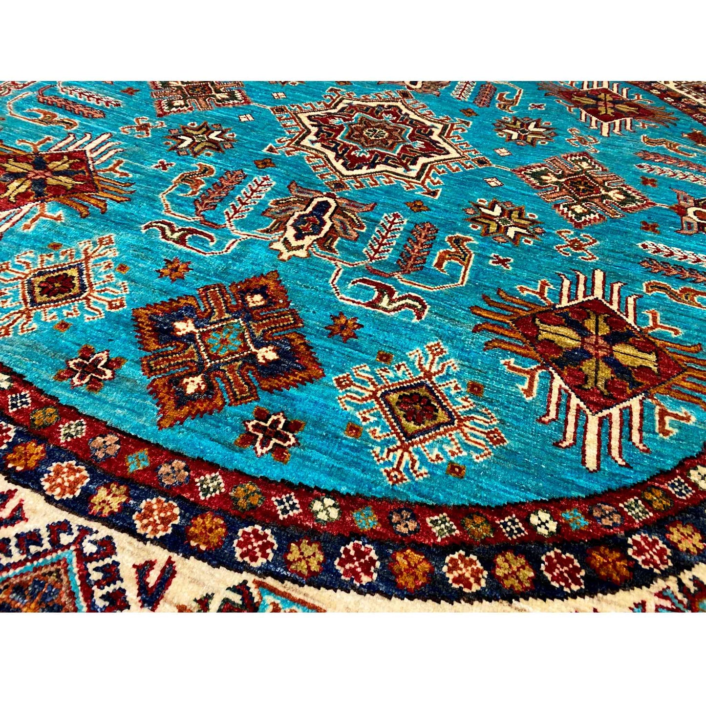 Close-up of a round rug: turquoise surface with multicolored animal and ornamental motifs