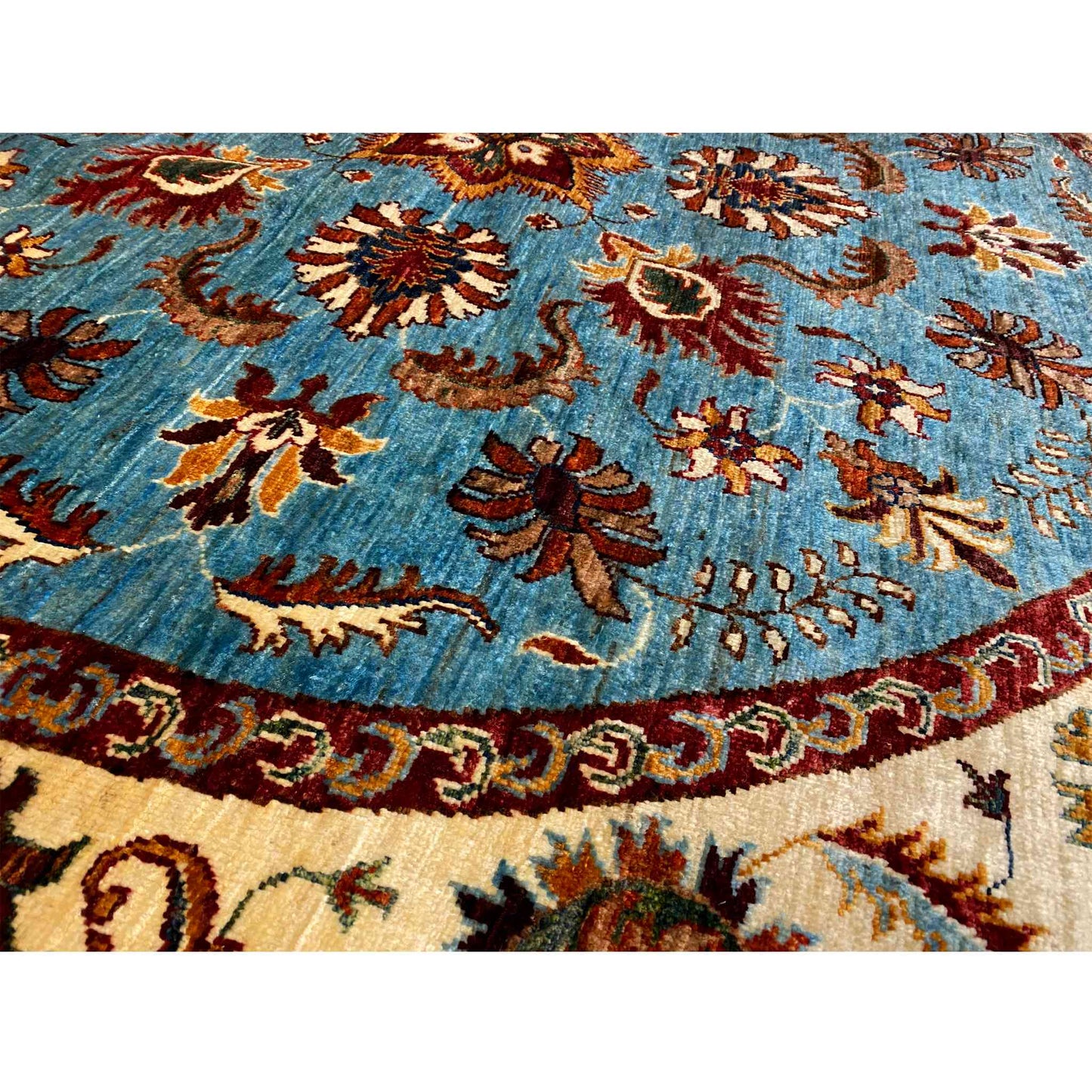 Close-up: blue floral field with multicolored rosettes, brown border along the edge