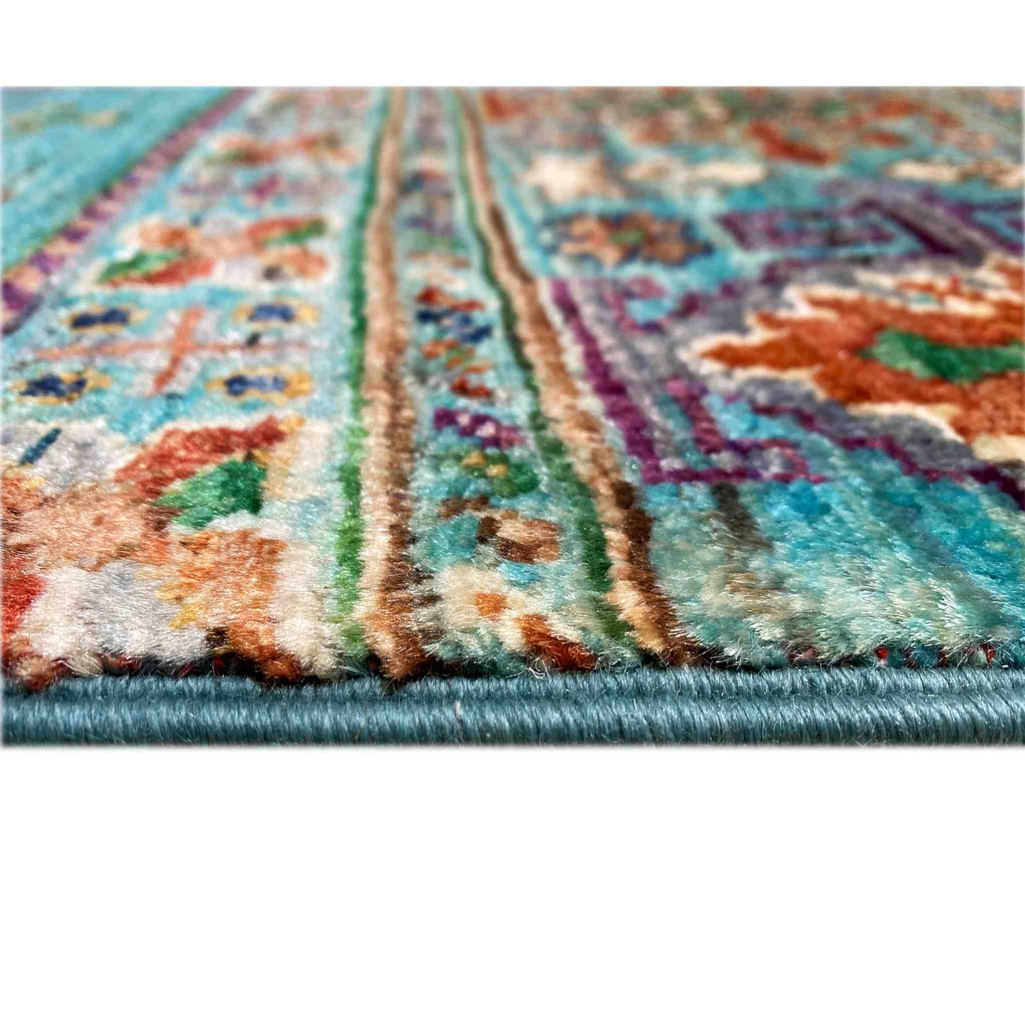 Close-up of a petrol-blue carpet surface with colorful ornaments and a short pile texture