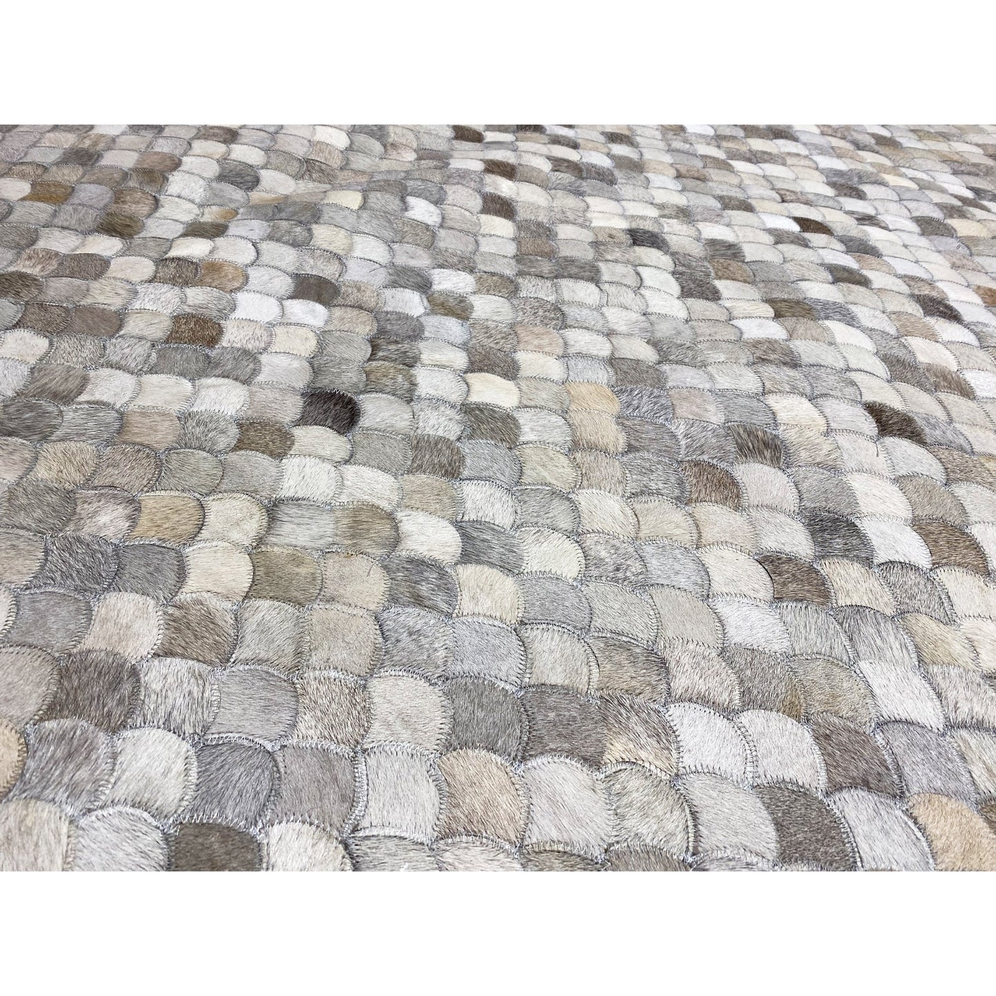 Shell calfskin rug detail view: overlapping shell segment pattern in gray/beige