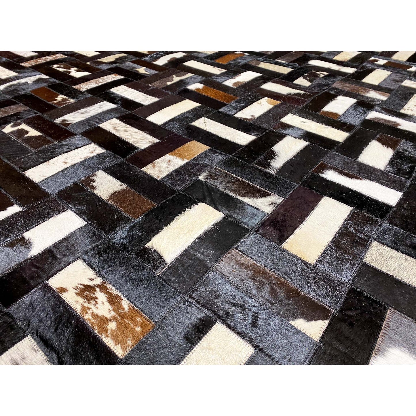 Close-up of a calfskin rug: dark blocks, light gray and white stripes, brown spots