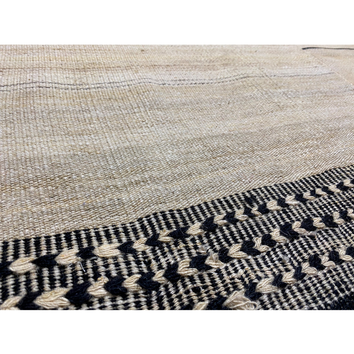 Kilim border in detail: dark gray zigzag pattern along the carpet edge