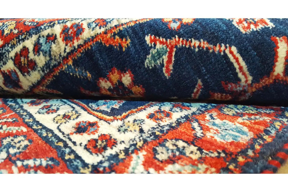 Blue rug with multicolored ornaments, rolled edge, and pile details