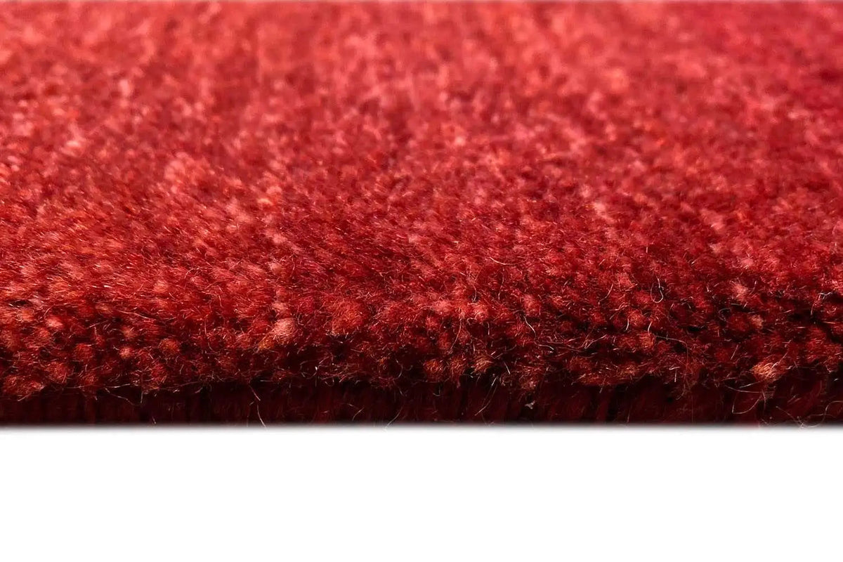 Carpet surface in burgundy with a dense pile structure along the edge
