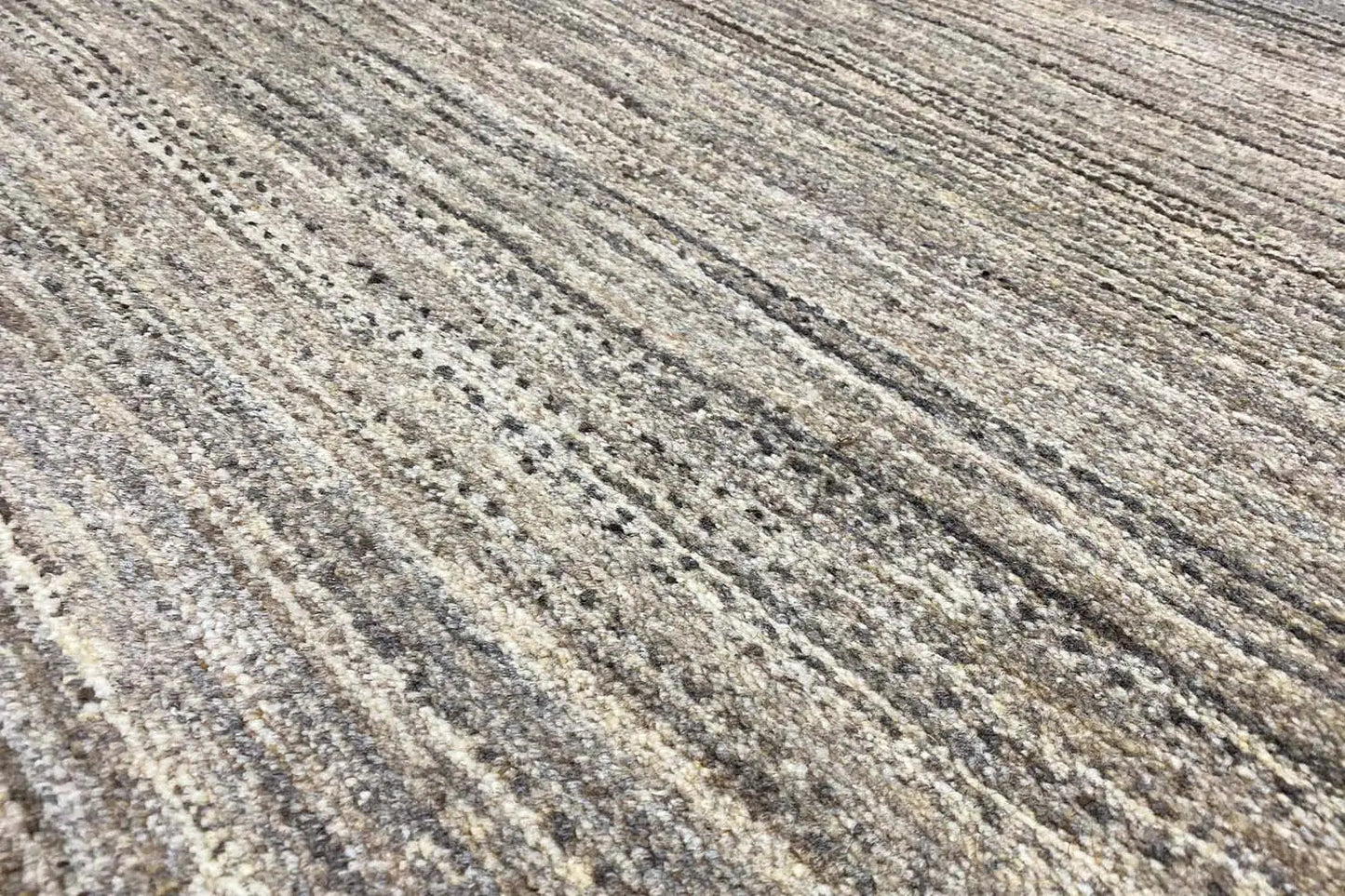 Close-up of a Gabbeh rug: gray-beige pile with long light and dark stripes
