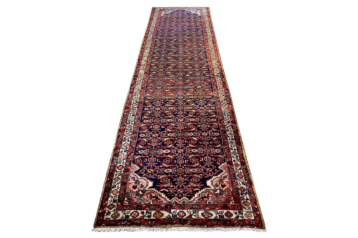 Oriental rug runner in a landscape format with a delicate red-and-blue pattern and beige central area, surrounded by a border.
