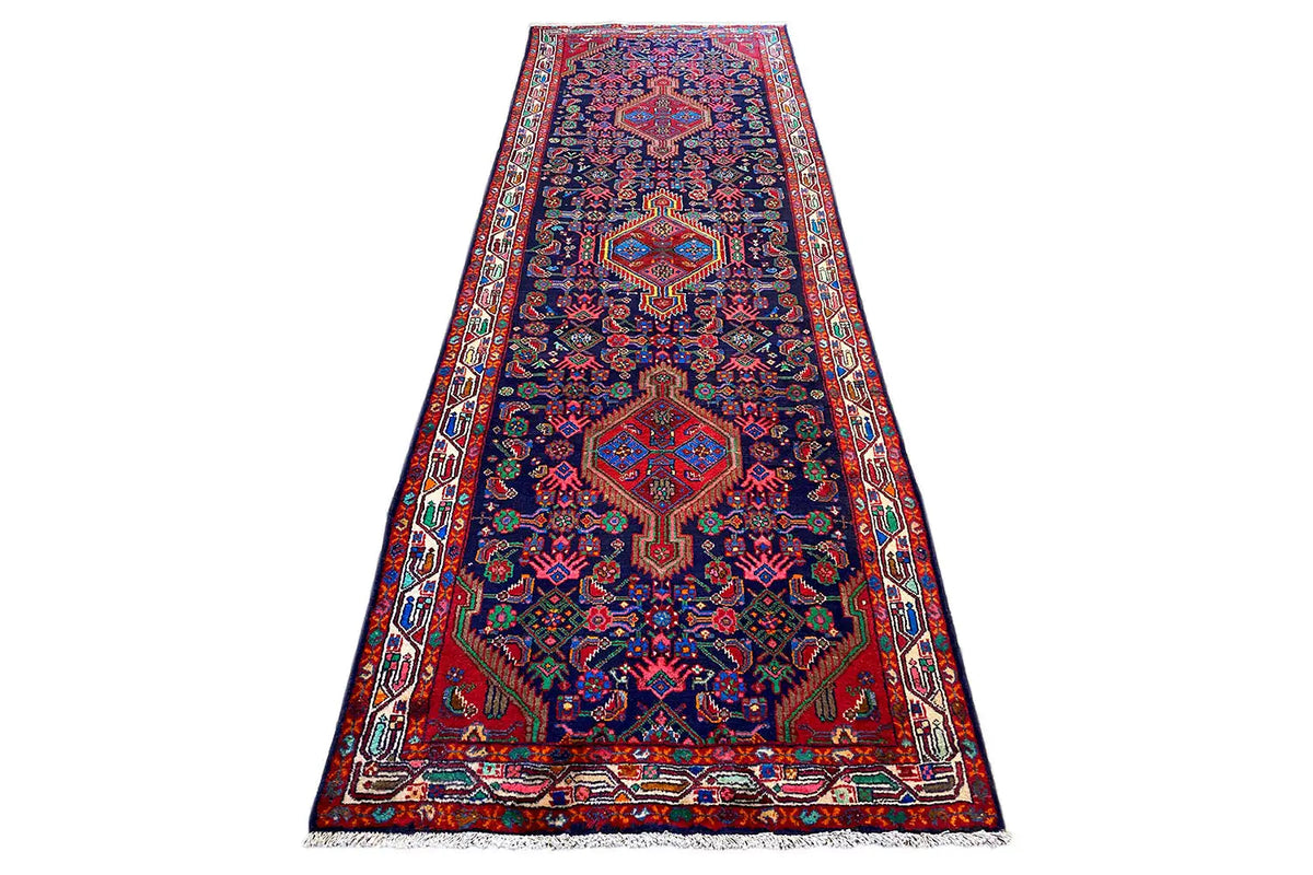Runner rug with a dark blue background, red and green ornaments, and a wide border