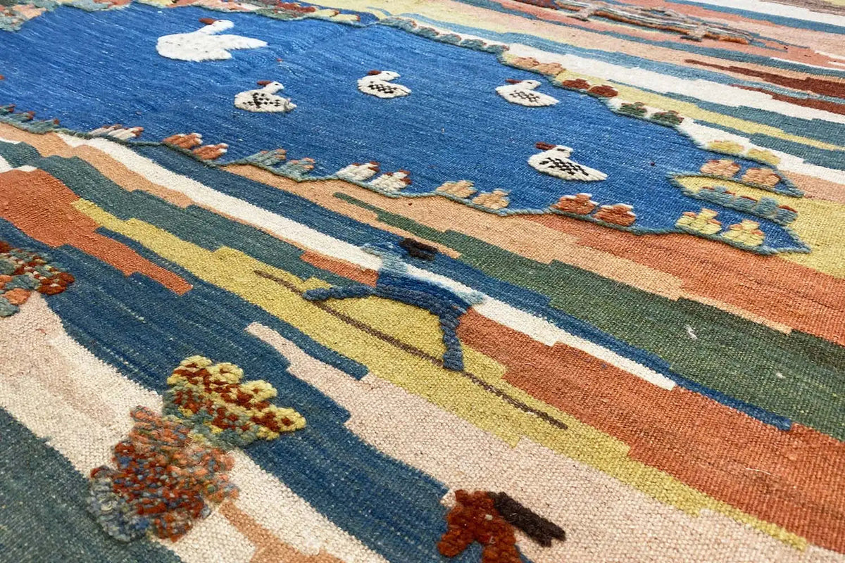 Close-up of a kilim rug with floral and animal motifs on a blue background