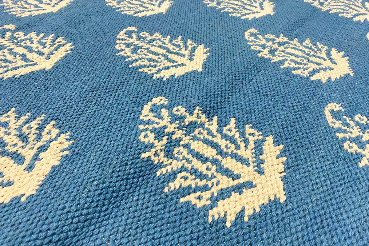 Blue kilim with cream-colored tree/branch motifs and a detailed woven texture.