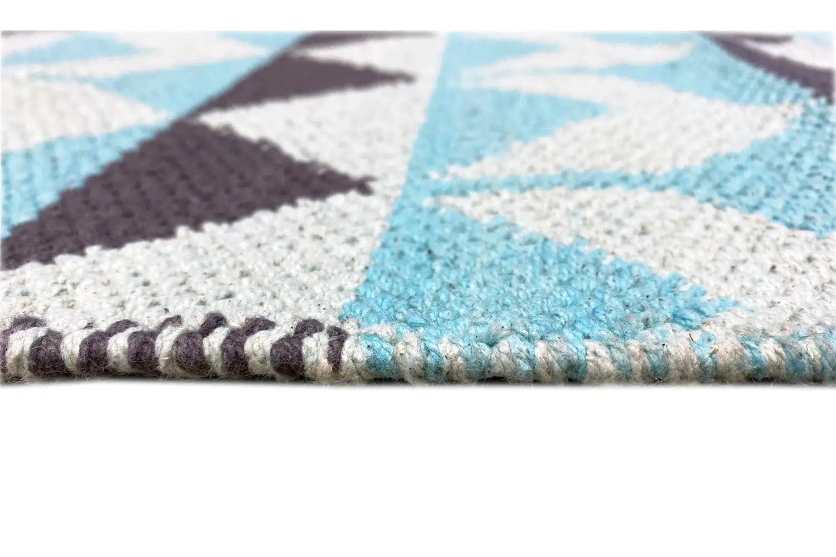 Carpet close-up: turquoise-white areas, dark accents, and brown knotted fringes