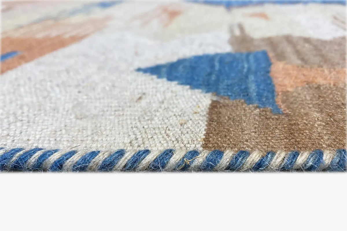 Kilim rug edge detail with fringes, blue pattern and beige texture