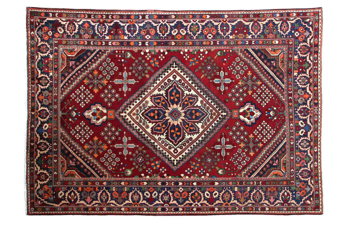 Rectangular oriental rug with a red patterned field, white diamond medallion and decorative border