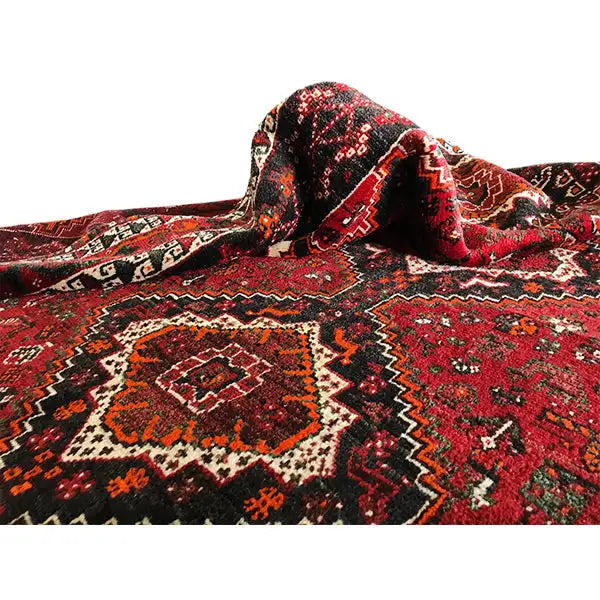 Folded red Oriental rug with ornate medallions and black border