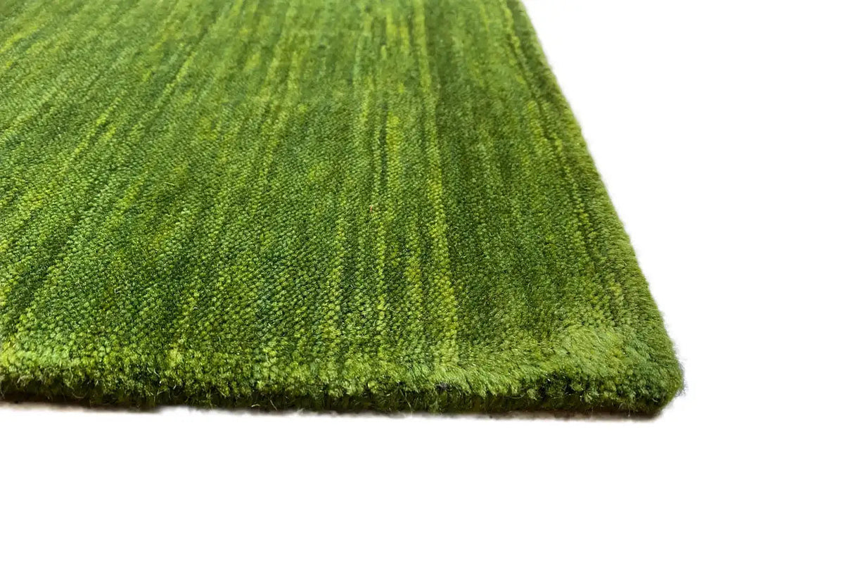 Corner of the Gabbeh rug: dense green pile with fine, lengthwise textures