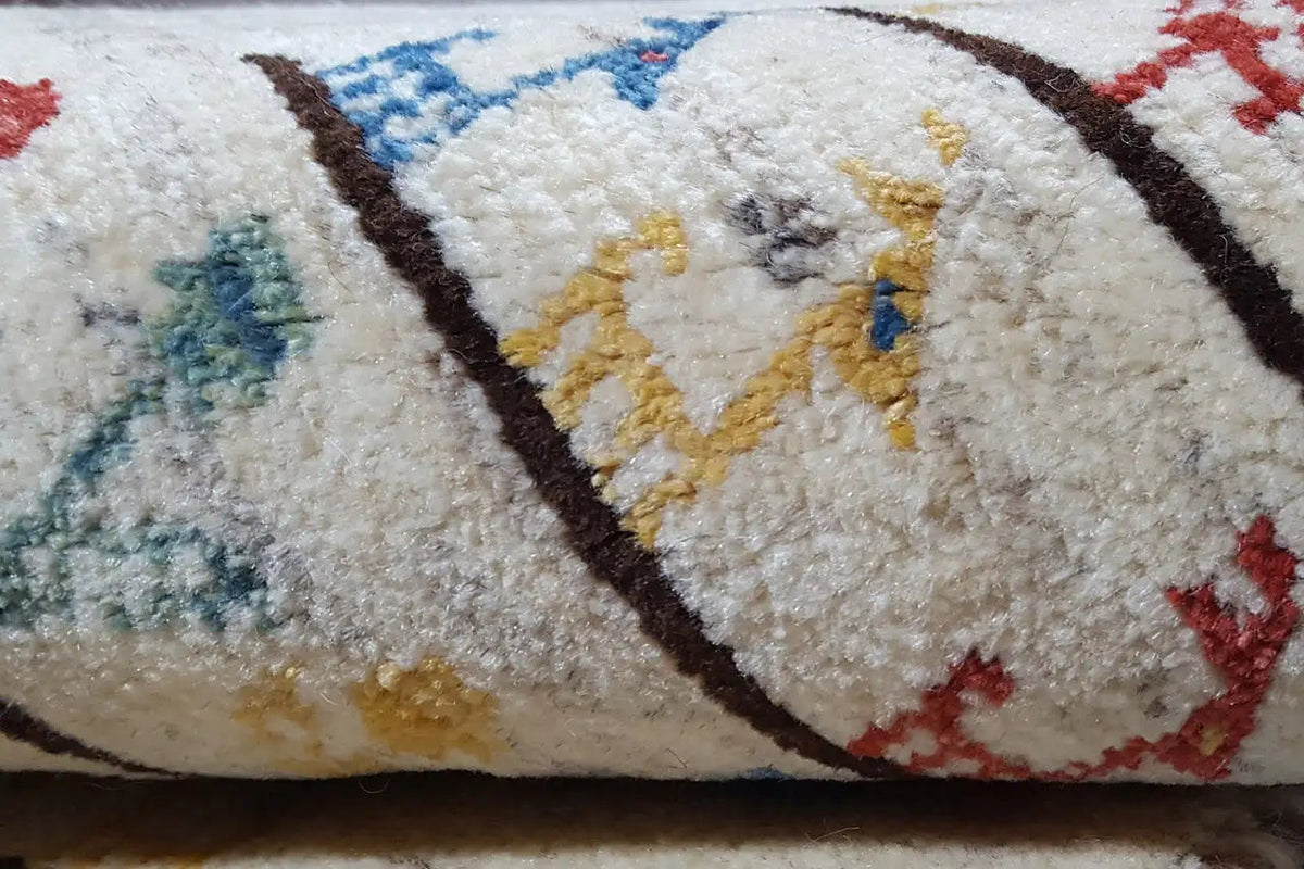 Close-up of Gabbeh rug: soft cream pile with colorful figures and outlines
