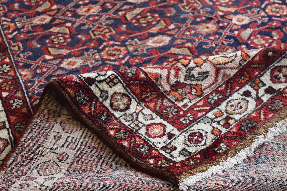 Oriental rug runner detail view: blue-red ornaments, cream-colored accents, and fringes