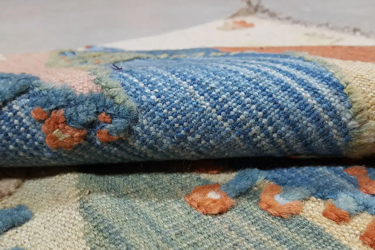 Kilim rug fold with a dense woven structure, blue segment, and relief-like fringe along the edge