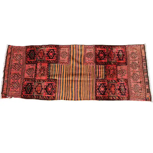 Kilim rug spread out horizontally with repeated patchwork panels in red and beige