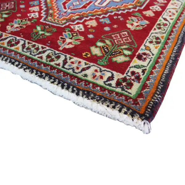 Carpet corner with fringe and decorative border; red background with colorful detailed motifs