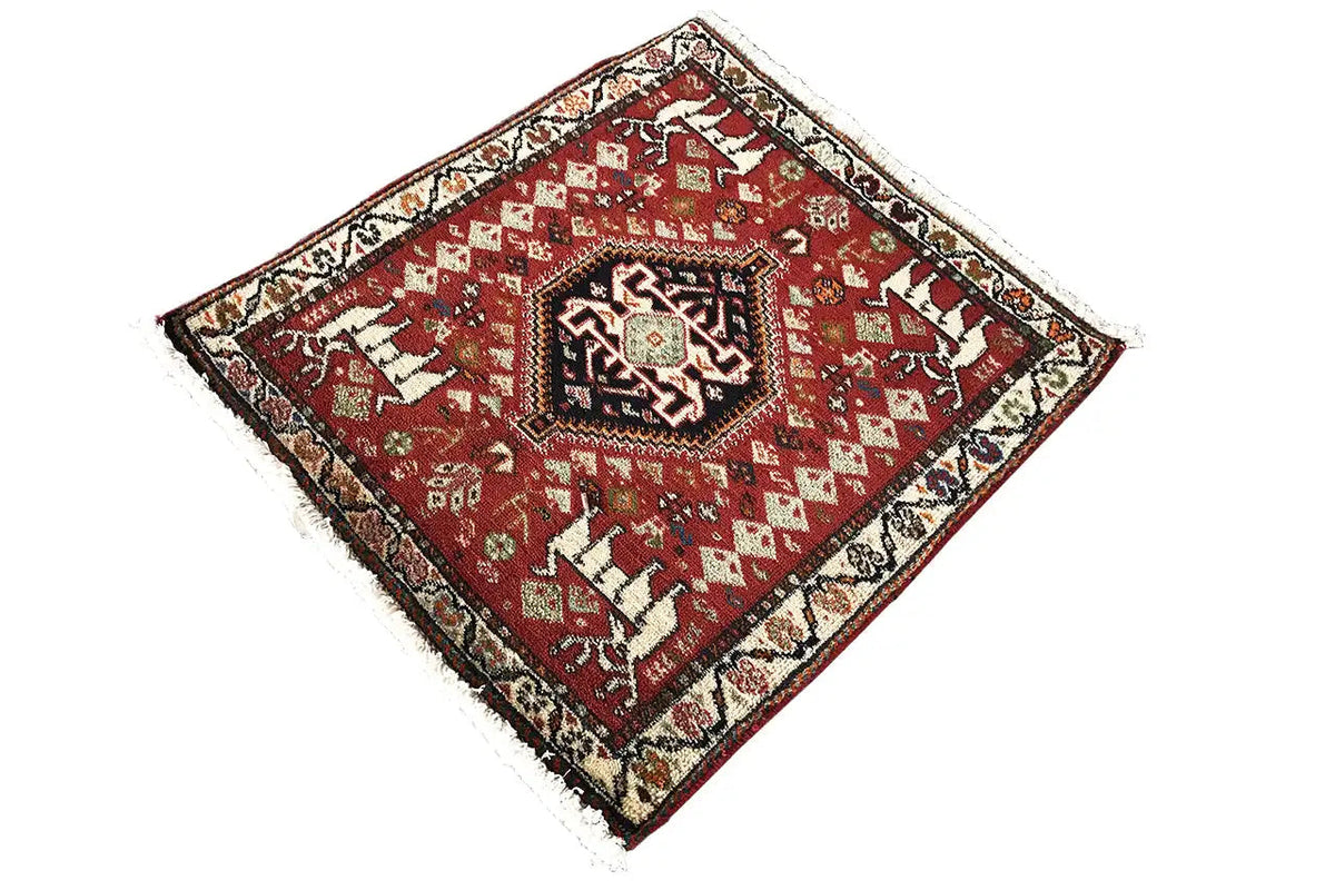 Square red rug with ornaments, a dark border, and fringe