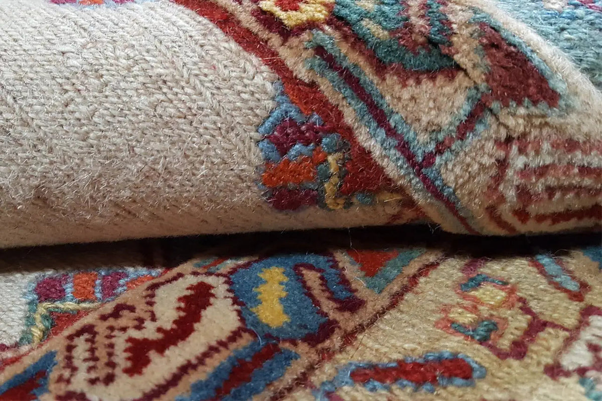 Soumak rug detail: beige pile with blue-red patterned stripes and embroidered motifs