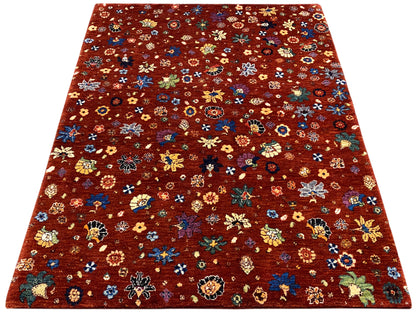 Teppichfläche mit rötlich-braunem Grund und bunten, floralen Motiven in klarer Musterung.