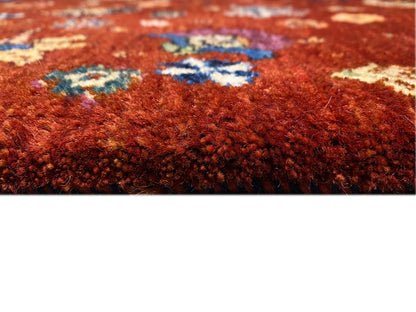 Teppichoberfläche im Detail: rötlich-brauner Flor mit bunten, eingewebten Mustern.