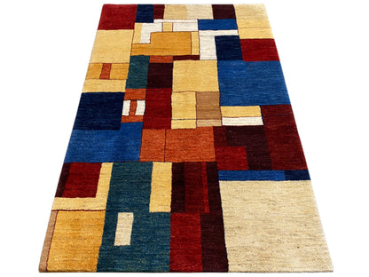 Gabbeh-Luri-Teppich im Dreiviertelblick: geometrische Kacheln in Rot, Blau und Beige.