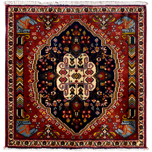 Poshti rug with a red background, dark blue octagonal pattern, and white border trim