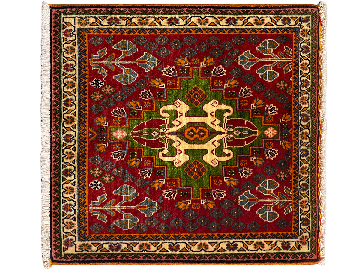 Oriental rug with a red background, green and beige medallion pattern, surrounding border, and fringe