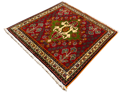 Red Oriental rug with a central cross motif, green accents, and a framed border