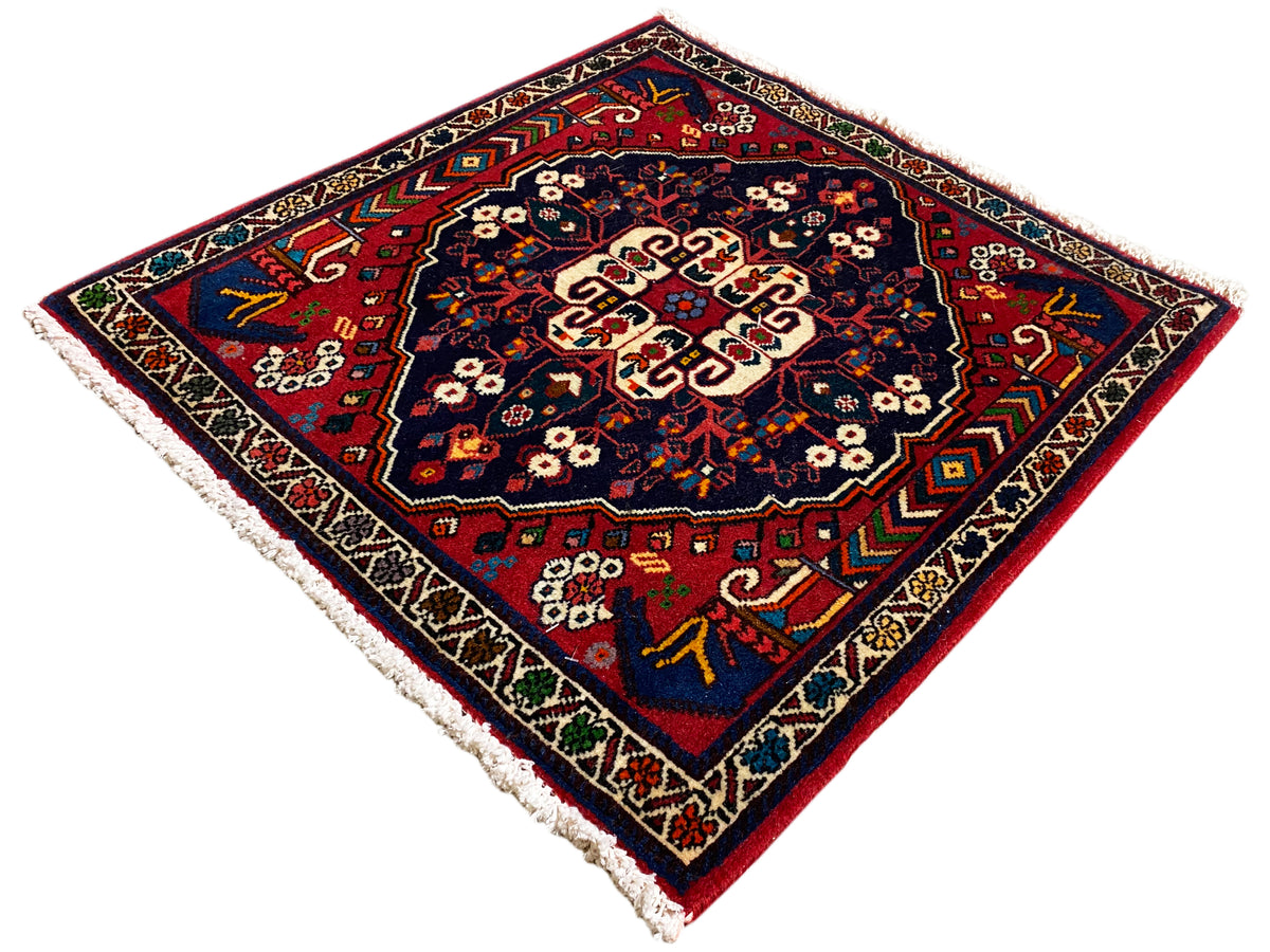 Square rug with a colorful ornament, deep-blue field, border motifs, and fringes