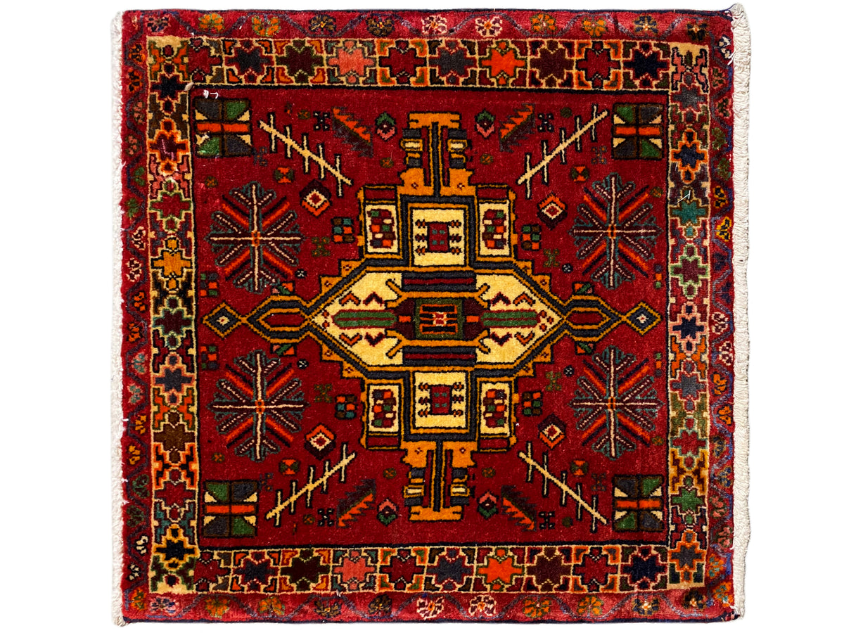 Rectangular Poshti rug with a red background and a multicolored geometric central motif