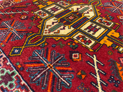 Close-up: Poshti rug with a red background and colorful geometric motifs