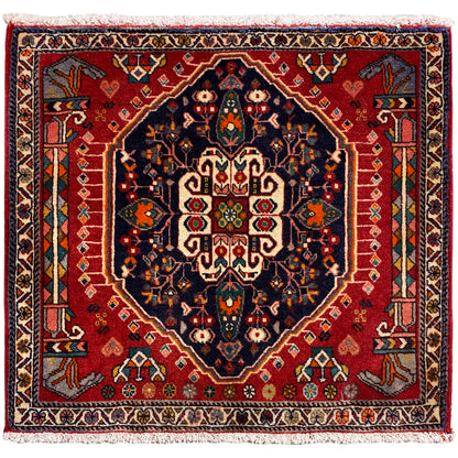 Square rug with a red background and dark blue central motif, with fringes