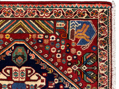 Carpet detail: red field with geometric motifs, blue corner motif, and border