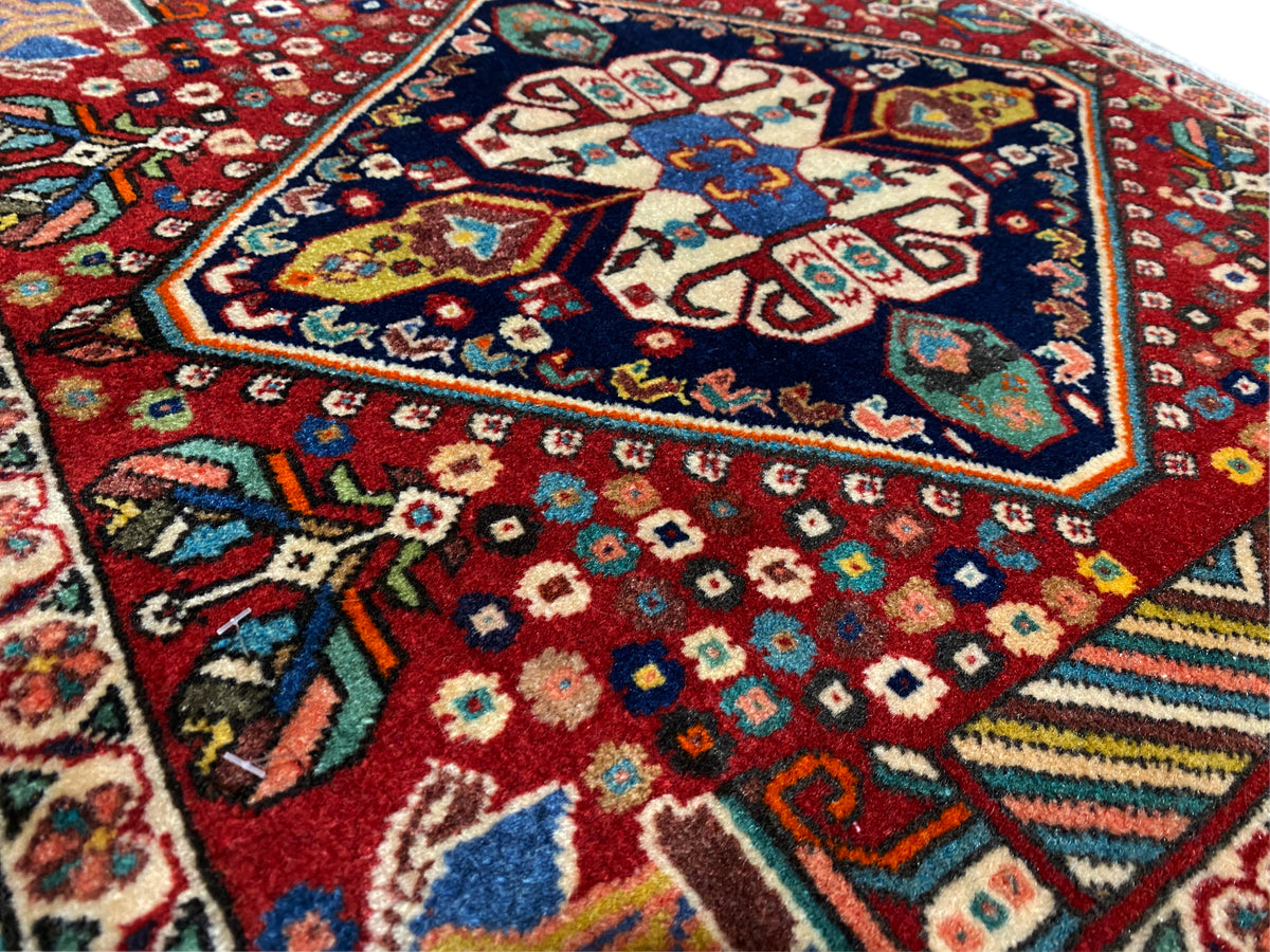 Carpet detail: colorful diamonds and floral patterns on a red background