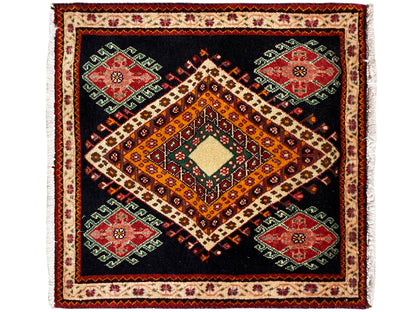 Poshti rug with a black background, an orange-yellow diamond, and four green and red medallions