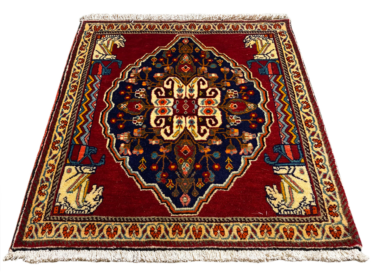 Rectangular rug with a red background, dark blue, and beige patterned borders
