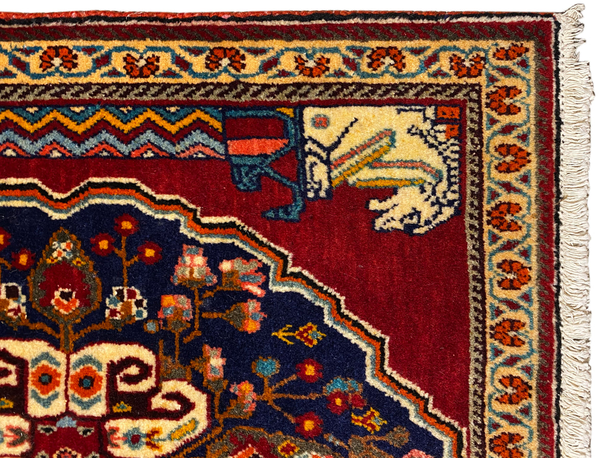 Detail view: red and dark blue carpet pattern with beige animal/figure elements