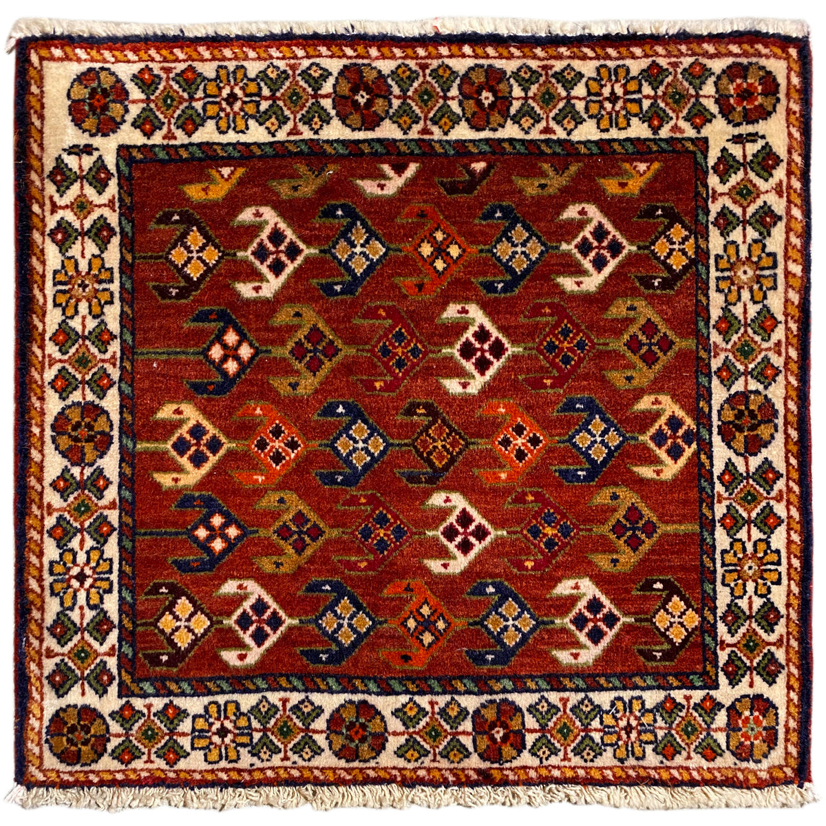 Square rug with a red background, a colorful white border, and fringes